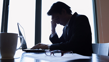 Person reviewing documents on a laptop with a concerned expression